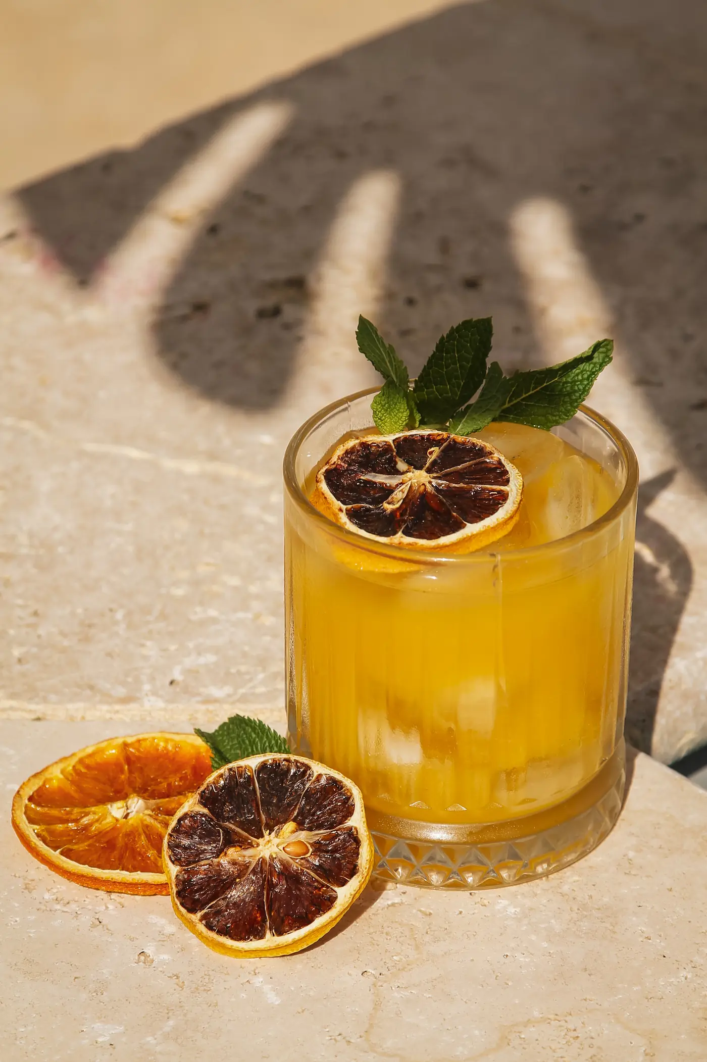 Cocktail Horizon, passion, mangue et vanille, garni d'une rondelle d'orange séchée et de menthe, en plein soleil