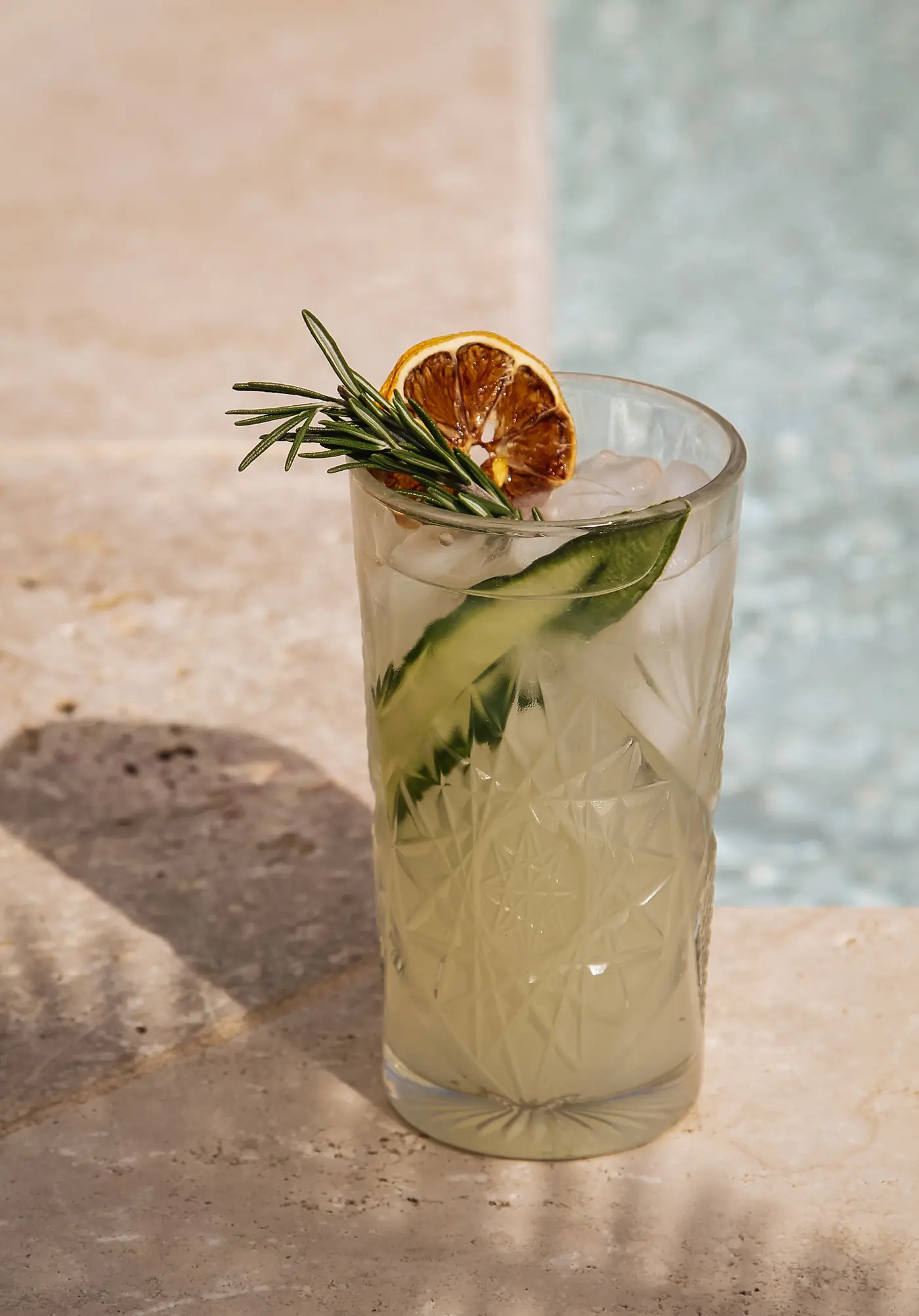 Cocktail Altitude au gin, concombre et romarin, servi en verre highball au bord de l'eau