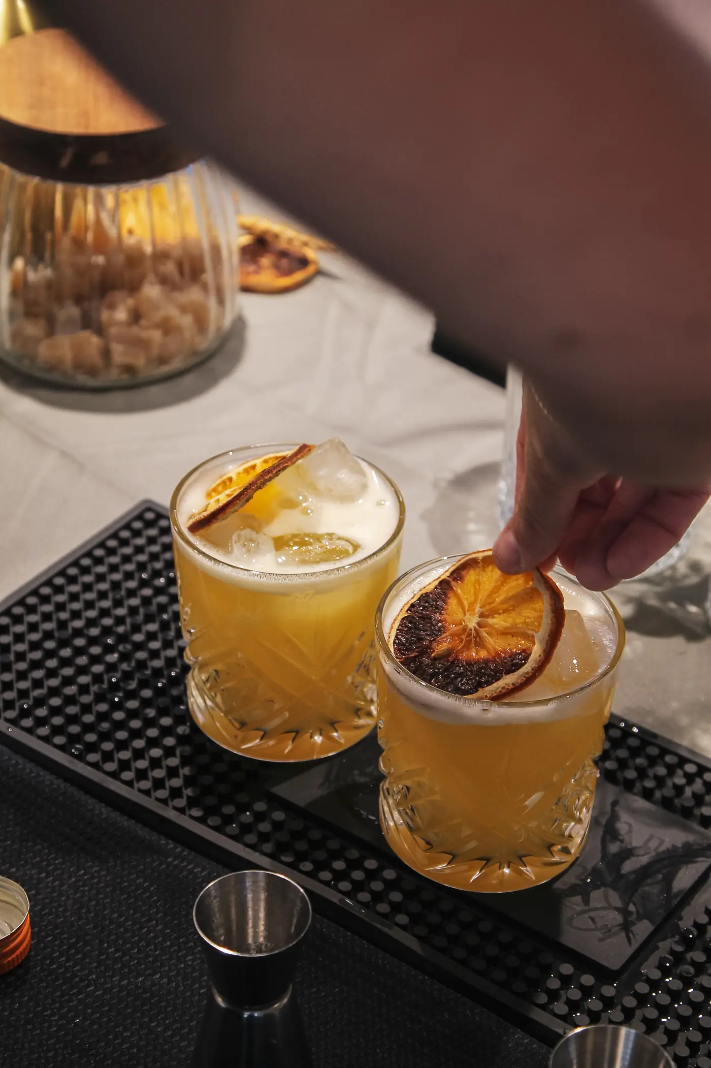 Finition d'un cocktail avec une rondelle d'orange séchée sur le bar