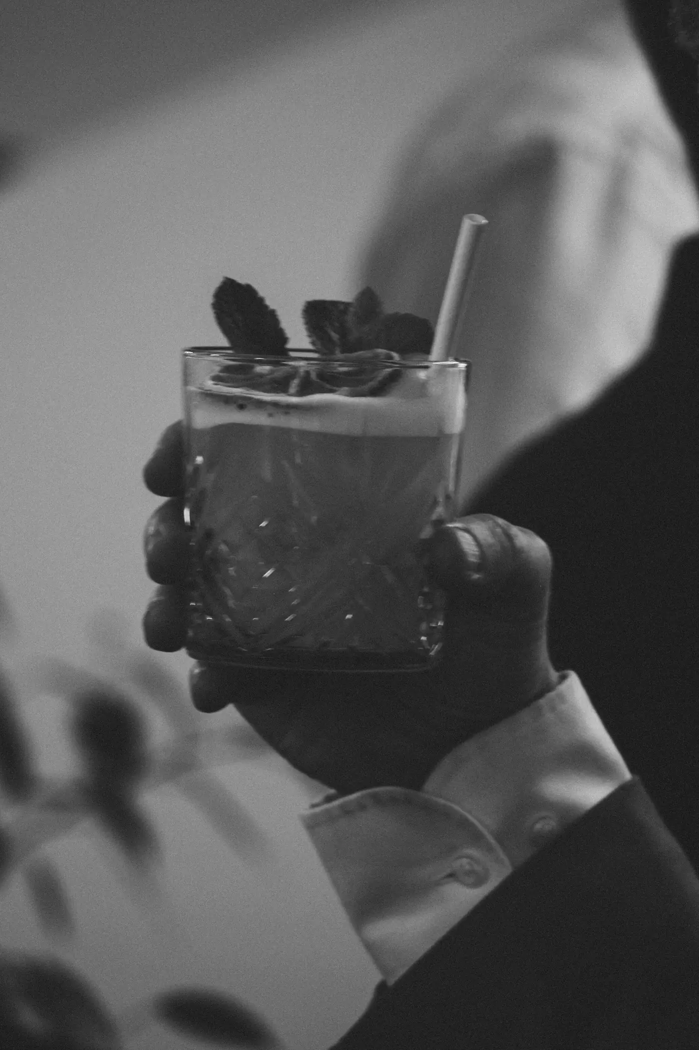 Invité tenant un cocktail garni de menthe, photo noir et blanc
