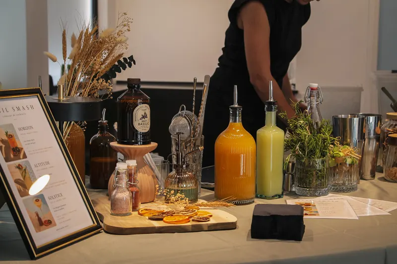 Le bar Basil Smash dressé pour un événement d'entreprise : carte encadrée, jus frais, sirops maison et herbes, créatrice de cocktails derrière le bar