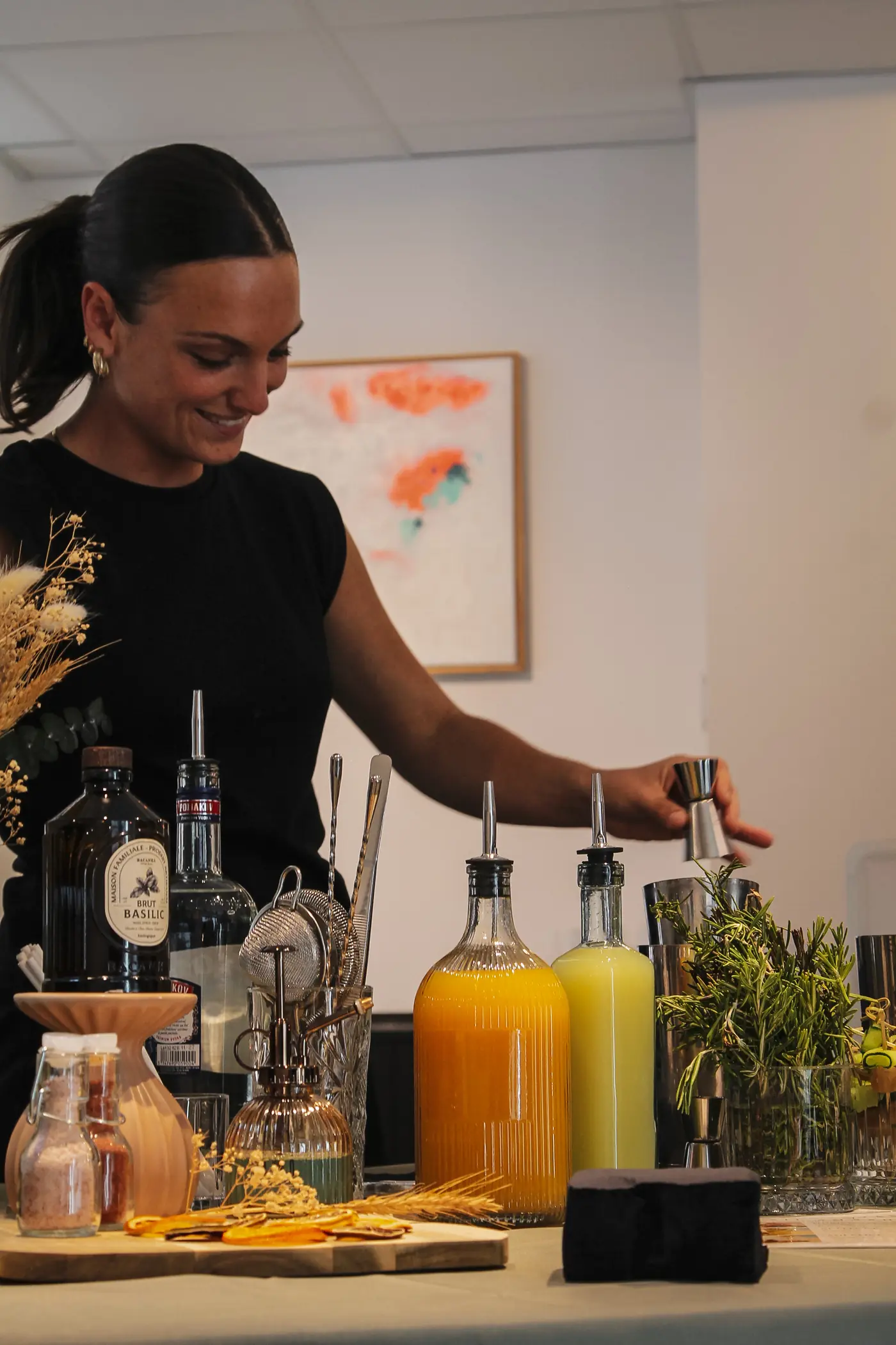 Lucile, créateur de cocktails Basil Smash, souriante derrière son bar à cocktails lors d'un événement