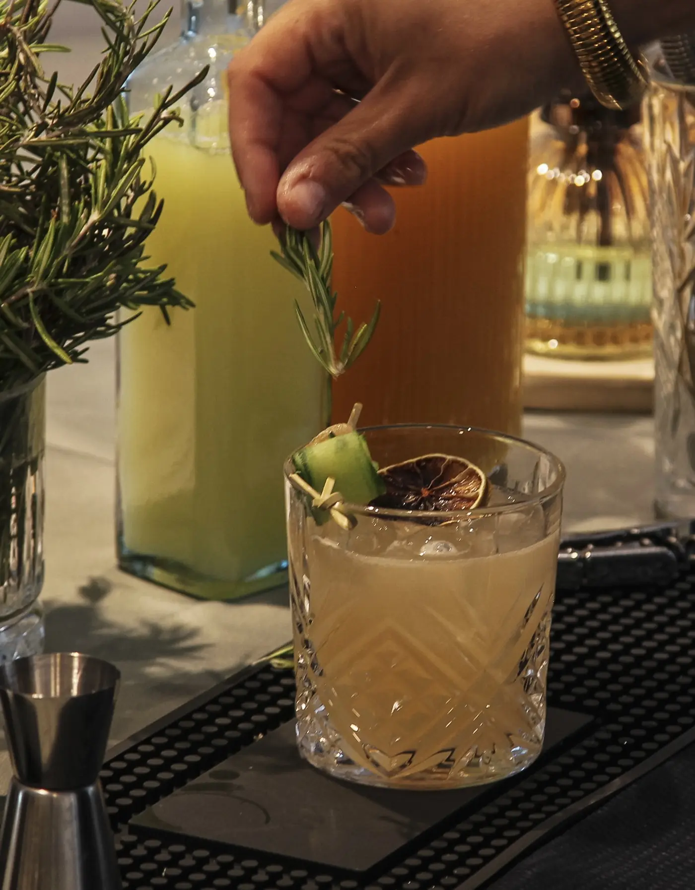 Cocktail garni d'une olive et de romarin, jus frais en arrière-plan